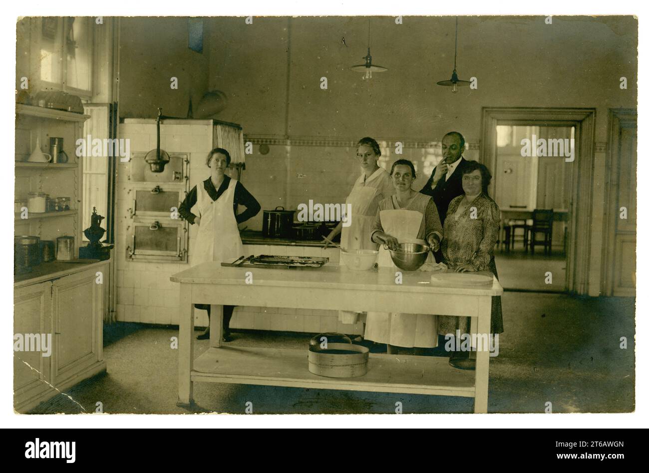 Cartolina originale degli anni '1920 con cuochi in una grande cucina domestica, cameriere, dirigente che indossa un abito a vita, piccolo hotel o istituzione, intorno al 1925. REGNO UNITO Foto Stock