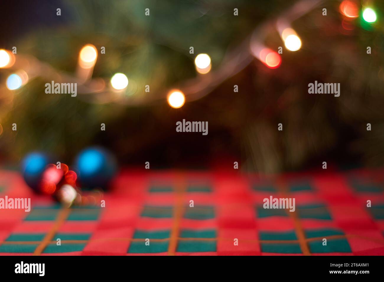 Sfondo natalizio orizzontale con decorazioni natalizie sfocate sul tavolo con tovaglie verdi e rosse, palle natalizie, albero e luci. Spazio copia f Foto Stock