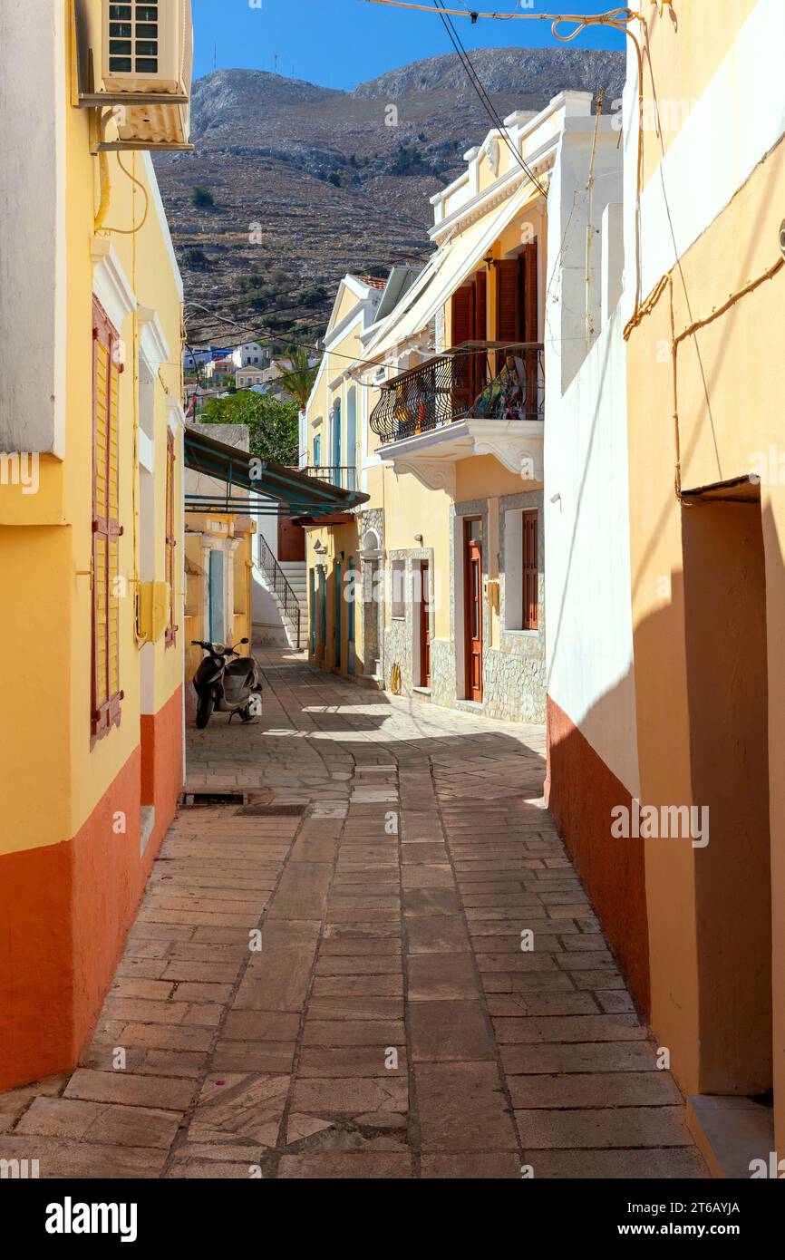 Facciate colorate delle tradizionali case greche multicolore su una stretta strada dell'isola di Symi. Foto Stock