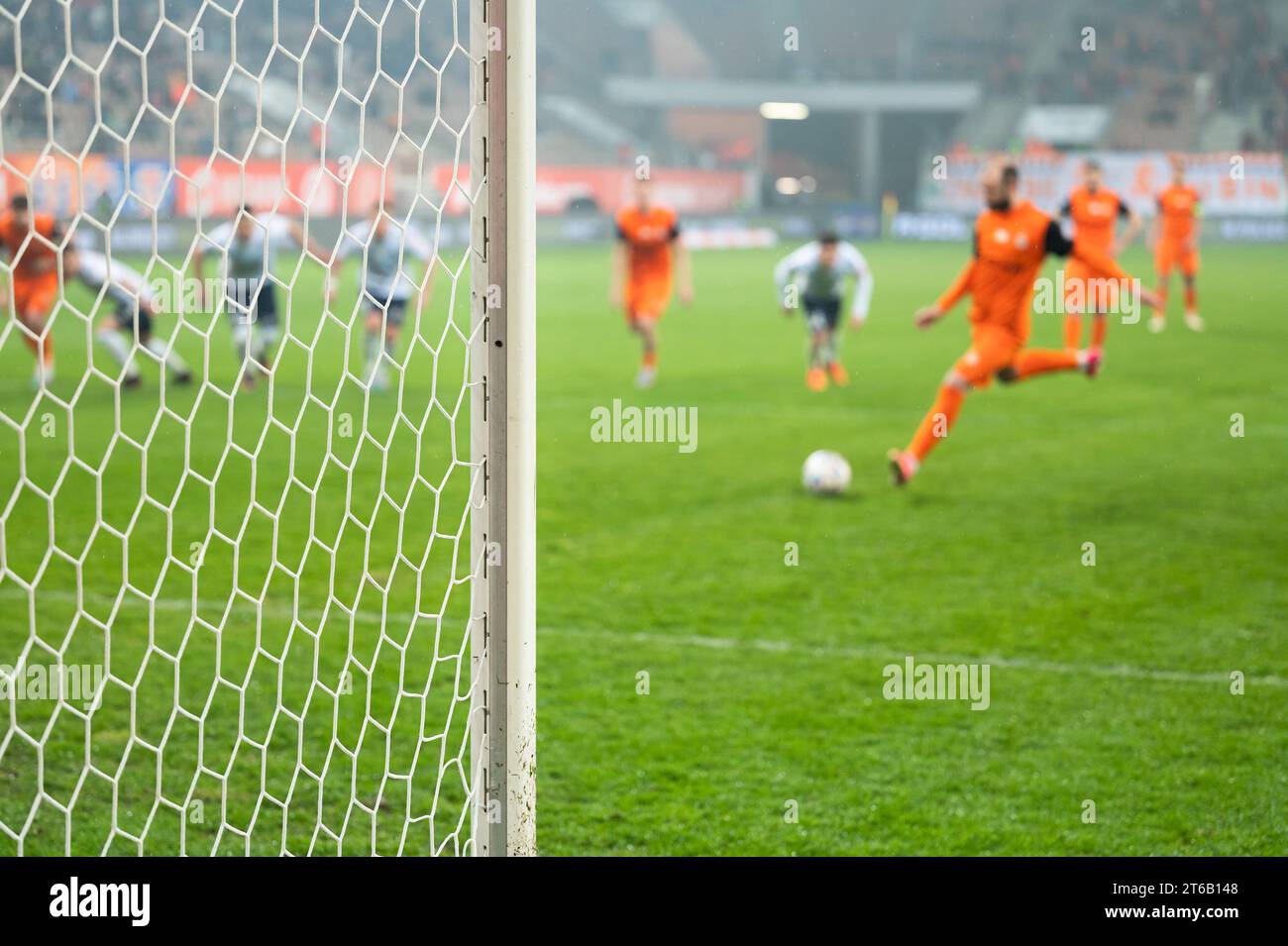 Dettaglio del post della porta con rete e giocatore di calcio durante il calcio di rigore in background. Foto Stock