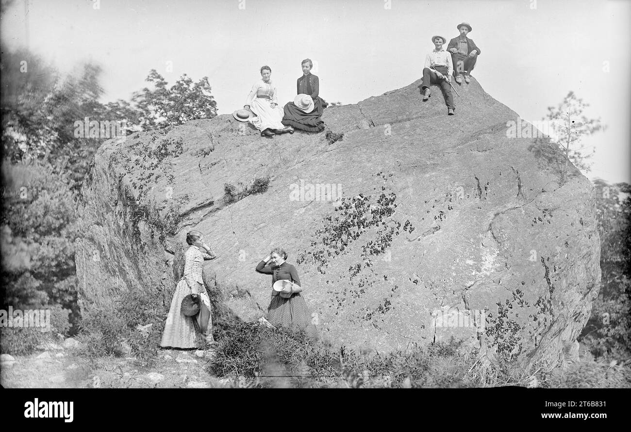 Antichità risalente al 1885 circa fotografia, gruppo di uomini e donne di mezza età all'aperto, arrampicata su una grande roccia; un uomo tiene una "tasca" o un "fucile da bicicletta". Posizione esatta sconosciuta, probabilmente Maine, USA. FONTE: ORIGINALE 5X8 VETRO NEGATIVO Foto Stock