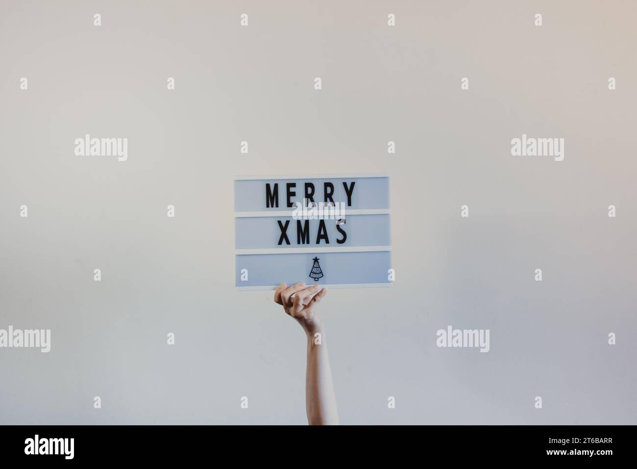 mano che regge un cartello minimalista con scritta natalizia allegra Foto Stock