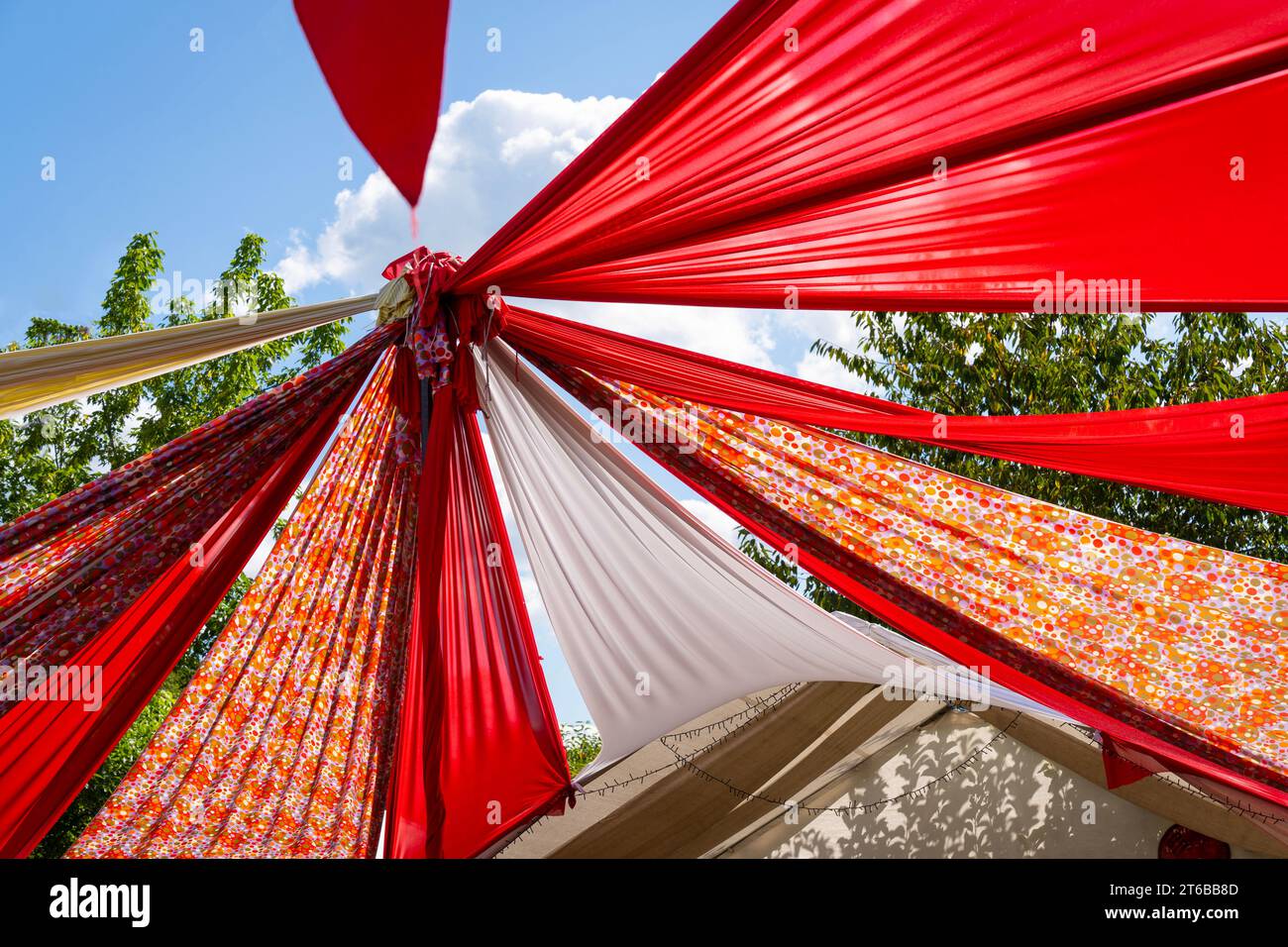 Tenda festival a motivi rossi e bianchi che dona ombra sotto il cielo blu Foto Stock