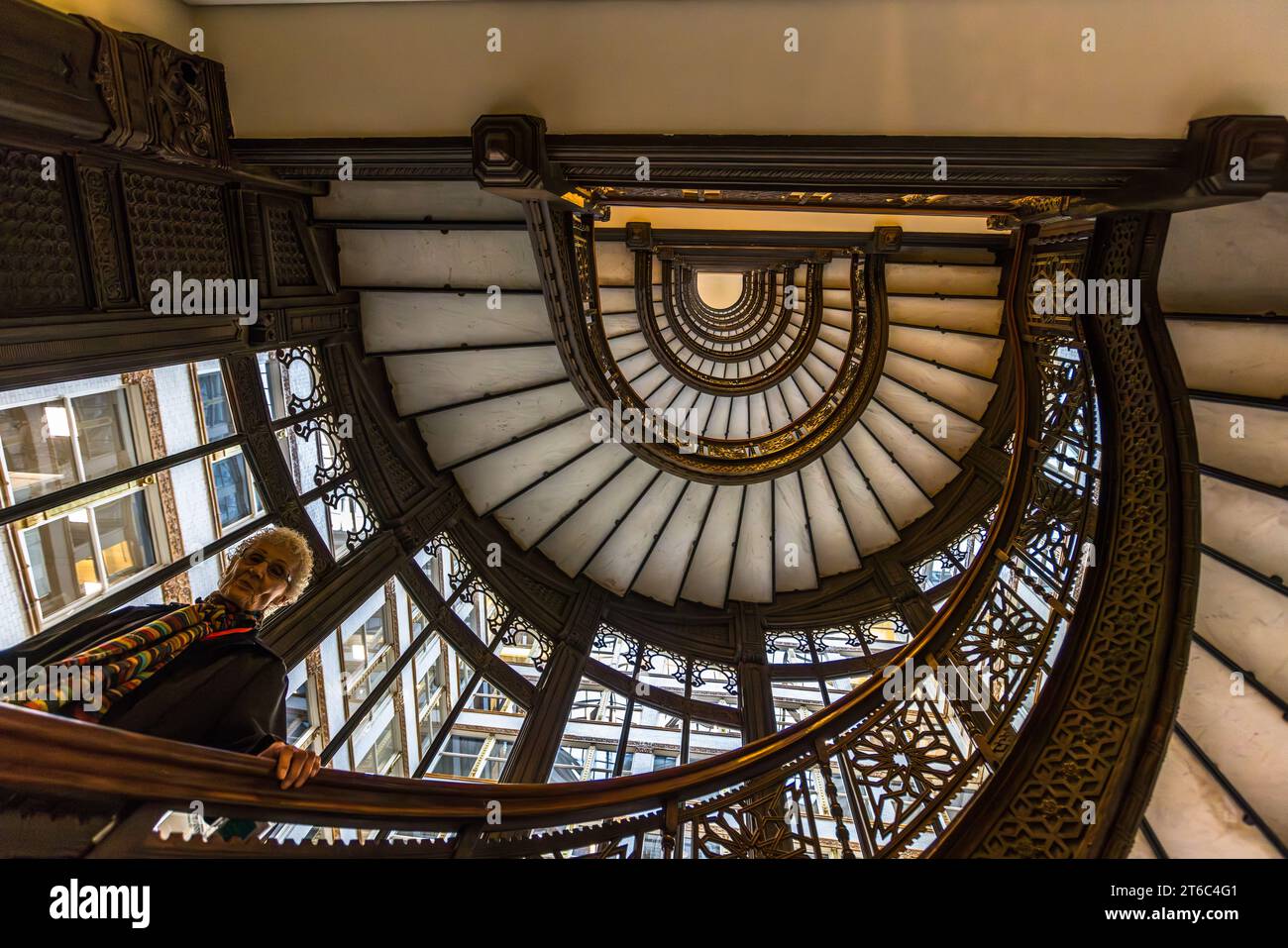 Un visitatore guarda verso l'alto verso le spirali della cosiddetta scala a erker sulla facciata ovest del Rookery Building a Chicago, Illinois, Stati Uniti. Foto Stock
