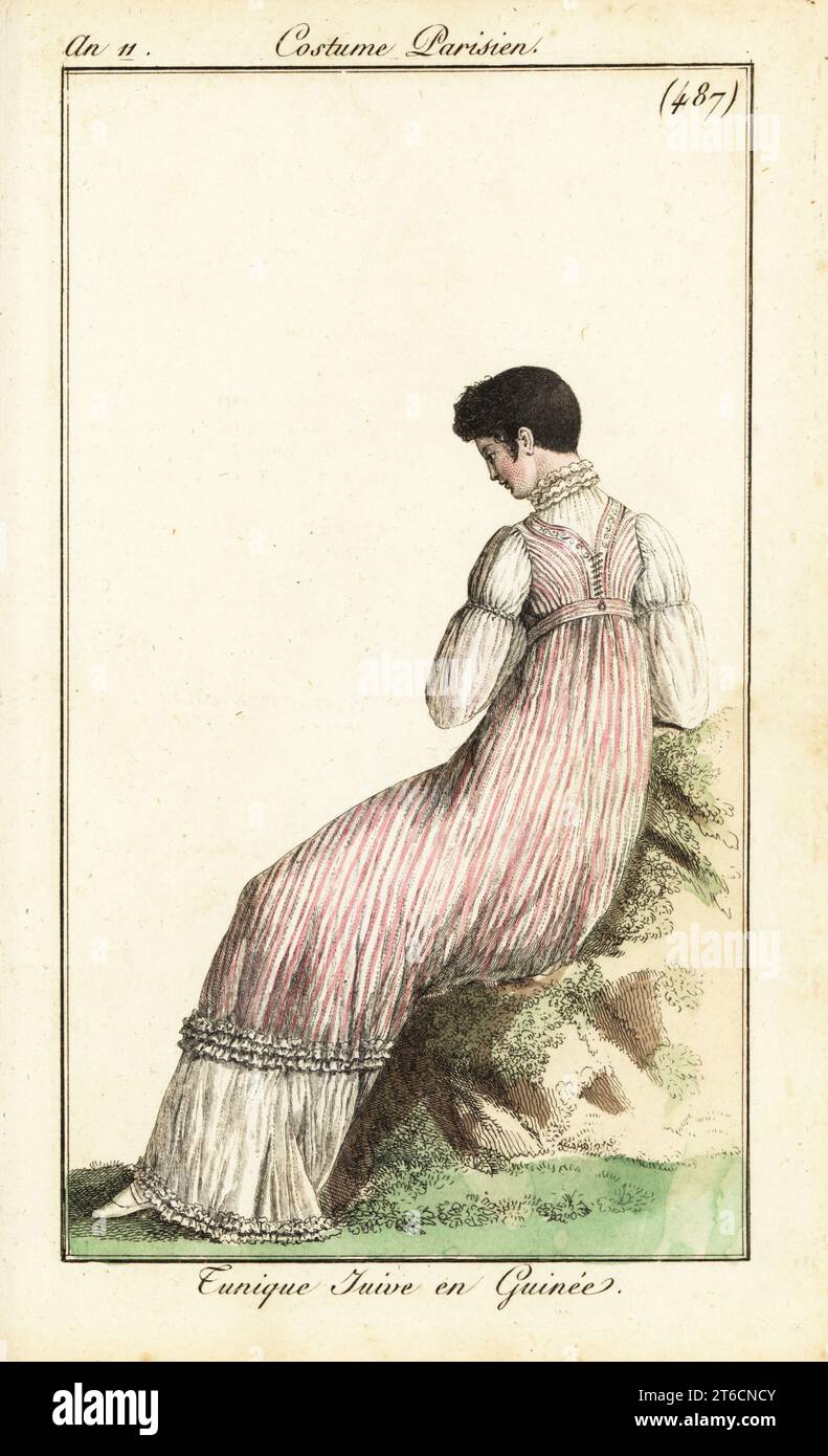 Donna alla moda con capelli corti a la Victime. Indossa una tunica calico su un abito lungo. Tunique Juive en Guinée. Incisione in copperplate a mano da Pierre de la Mesangeres Journal des Dames et des Modes, Magazine of Women and Fashion, Paris, An 11, 1803. Illustrazioni di Carle Vernet, Jean-Francois Bosio, Dominique Bosio e Philibert Louis Debucourt, incise da Pierre-Charles Baquoy. Foto Stock