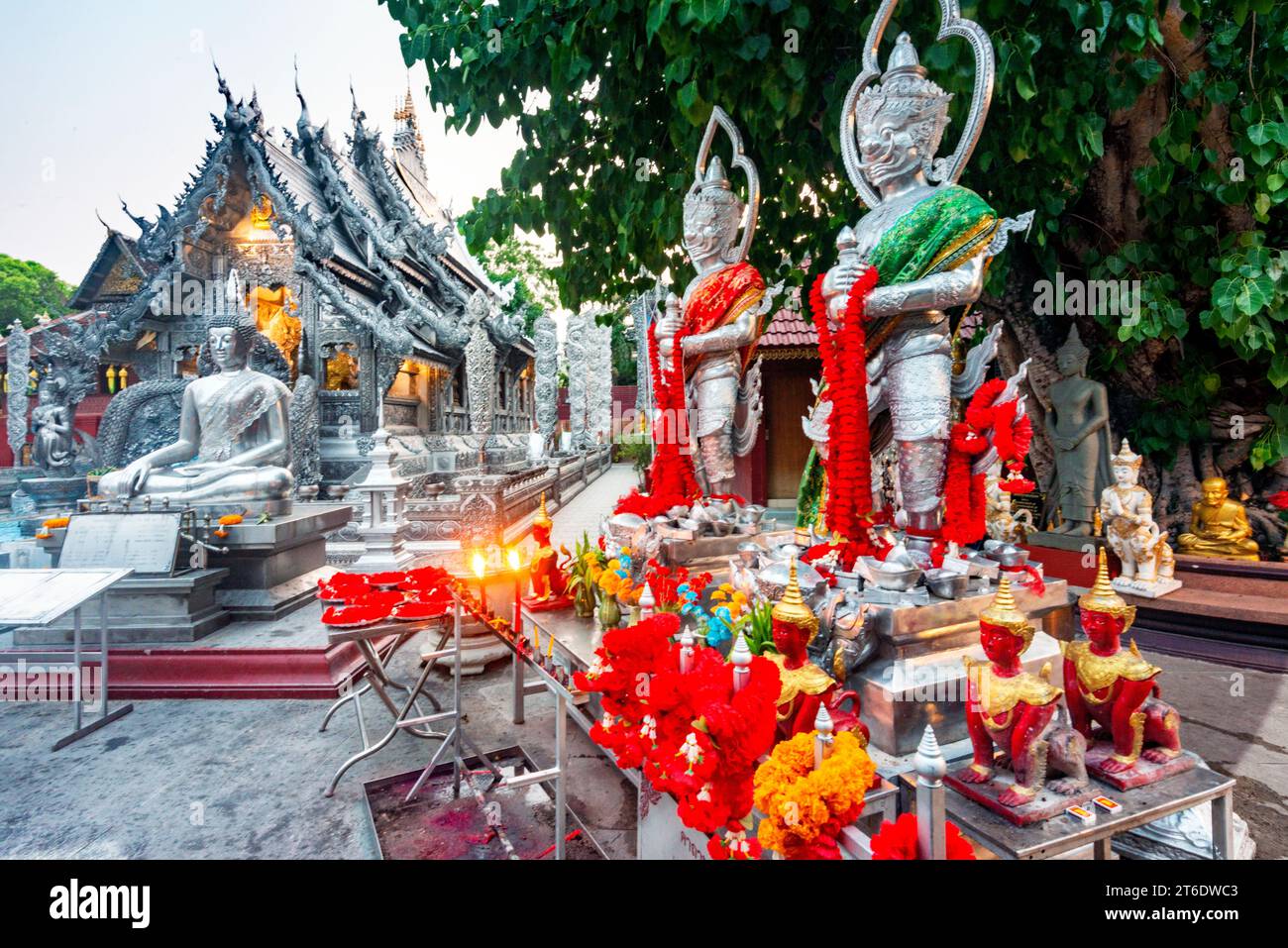 Tavoli con fiori rossi e arancioni, ghirlande sacre, candele accese, statue e incenso, prima di uno dei templi più belli di Chiang mai. Struttura unica Foto Stock