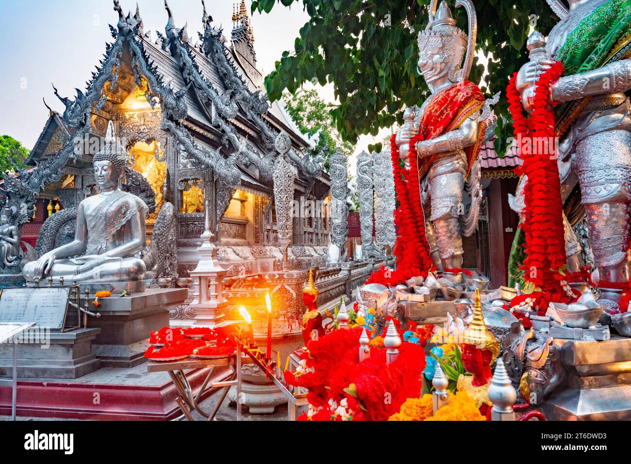 Tavoli con fiori rossi e arancioni, ghirlande sacre, candele accese, statue e incenso, prima di uno dei templi più belli di Chiang mai. Struttura unica Foto Stock