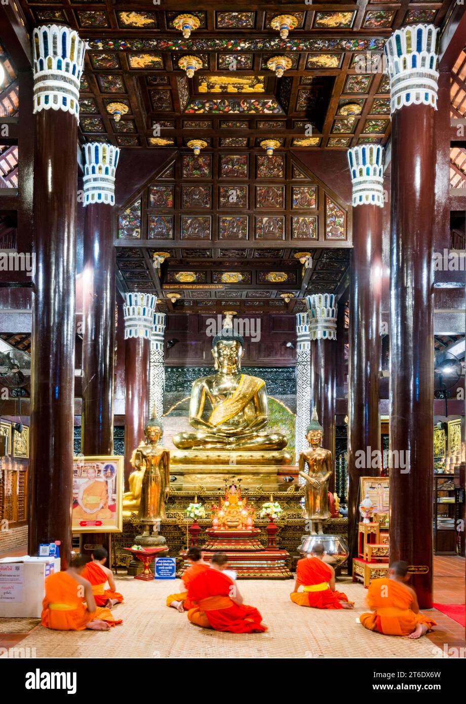 Chiang mai, Thailandia - 20 marzo 2023: Illuminata da luci all'interno dell'antica struttura in legno di teak, i monaci cantano durante le preghiere serali, prima della B dorata Foto Stock