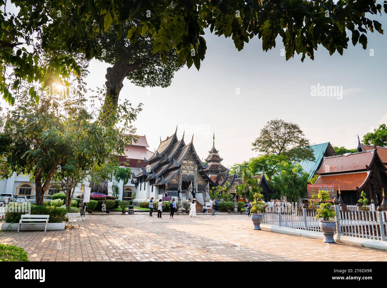 Chiang mai, Tailandia-20 marzo 2023: Il sole nel tardo pomeriggio sprofonda, all'esterno, l'antica struttura buddista in legno scolpito di Lanna, mentre la gente girovagava per la pace Foto Stock