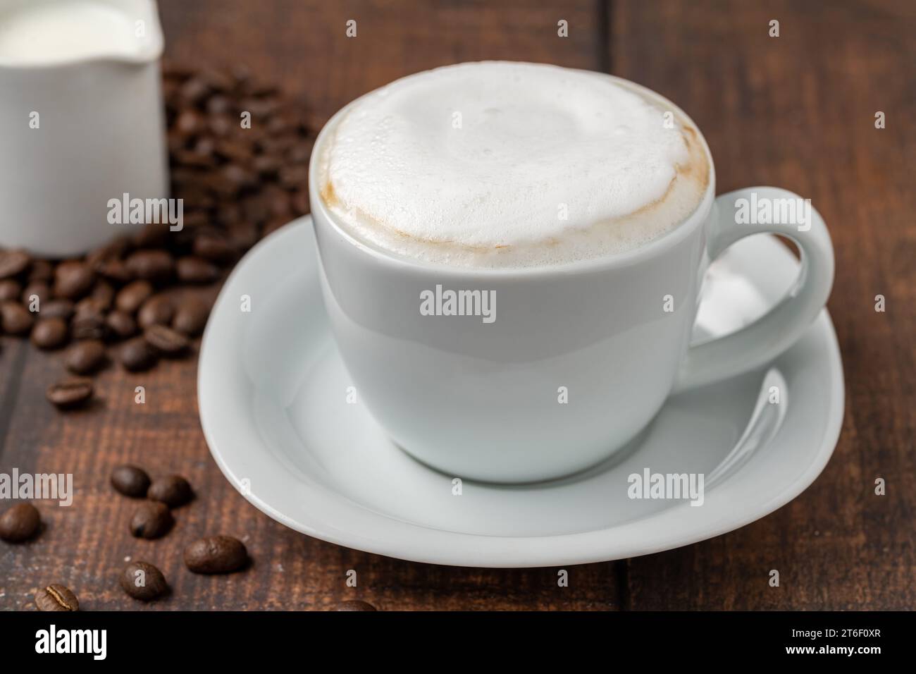 Cappuccino in una tazza di porcellana bianca su un tavolo di legno Foto Stock