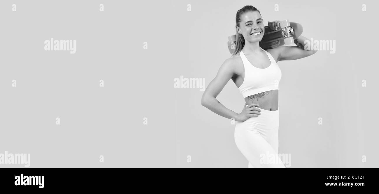 Happy fit ragazza skater tenere pennyboard sfondo giallo, penny board. Donna isolato volto ritratto, banner con mock su copyspace. Foto Stock