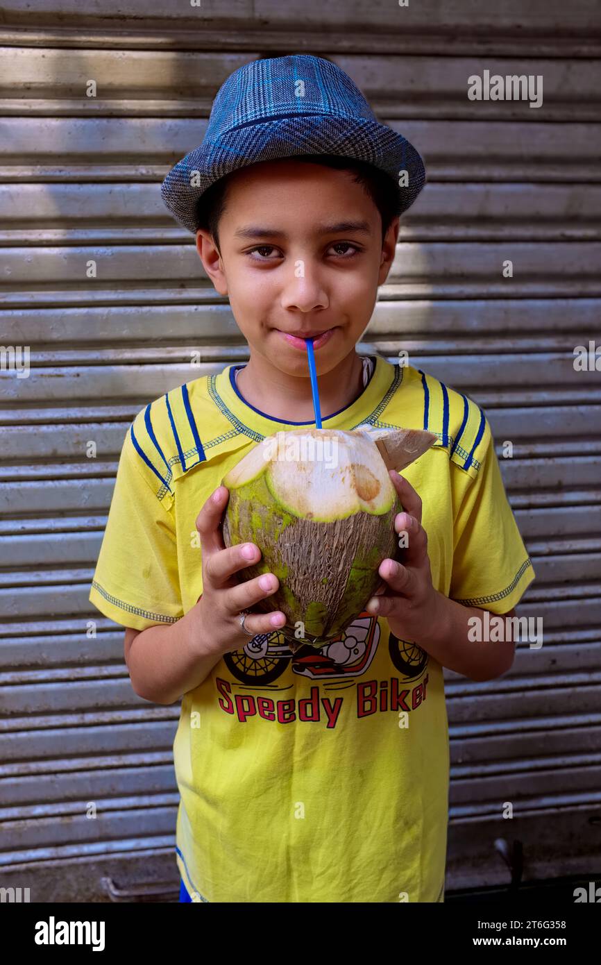 Un ragazzo indiano vestito nattiziamente a Mumbai, in India, che si rinfrescava l'acqua di cocco da una noce di cocco fresca Foto Stock