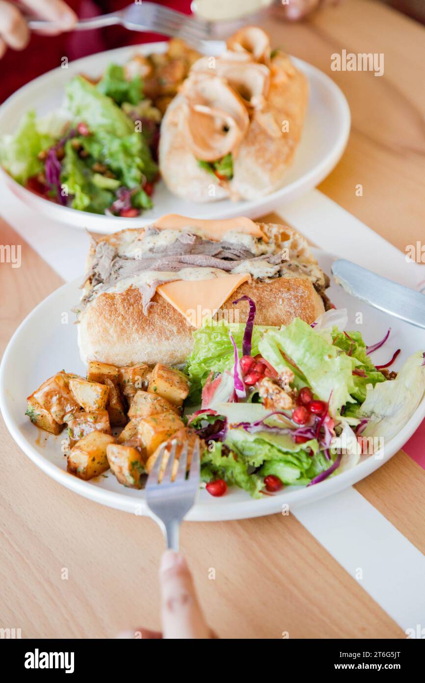 La gente che ha un cibo informale si incontra con sanwiches e fast food a pranzo. Foto Stock