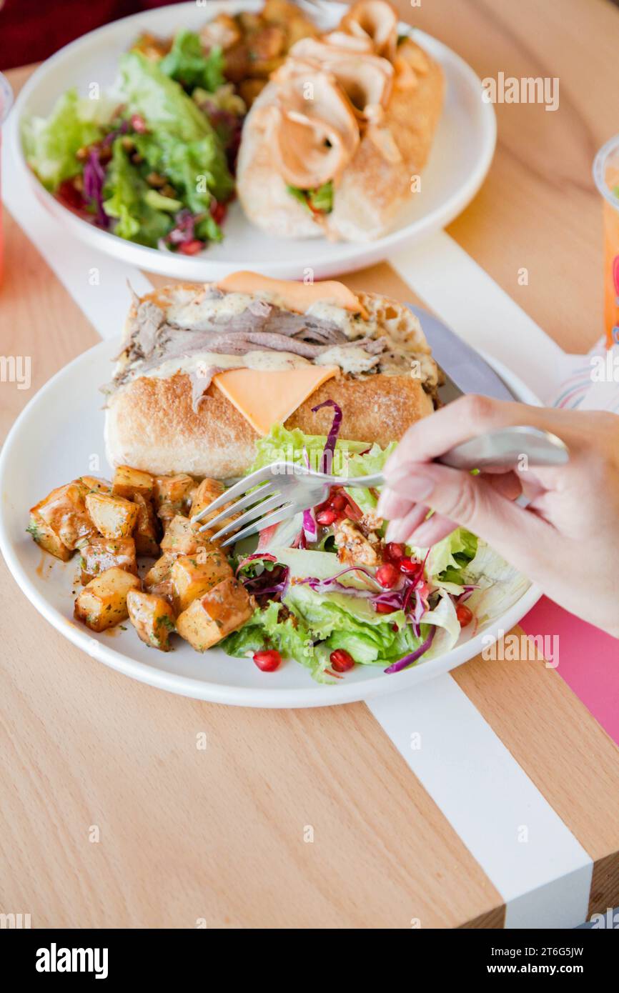 La gente che ha un cibo informale si incontra con sanwiches e fast food a pranzo. Foto Stock