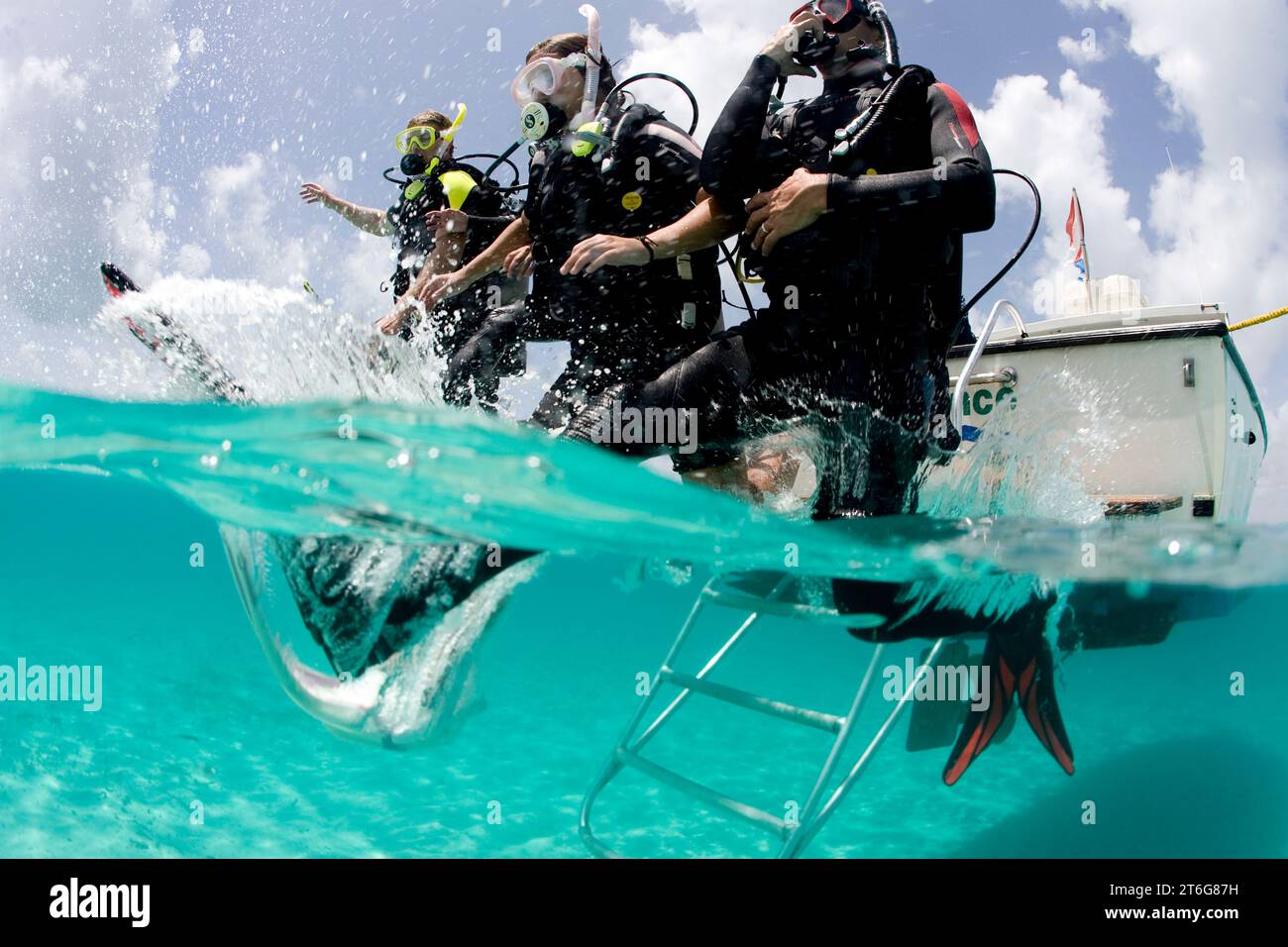 Foto di tipo over/under di subacquei che entrano in acqua dalla barca, Key largo, Florida. Foto Stock