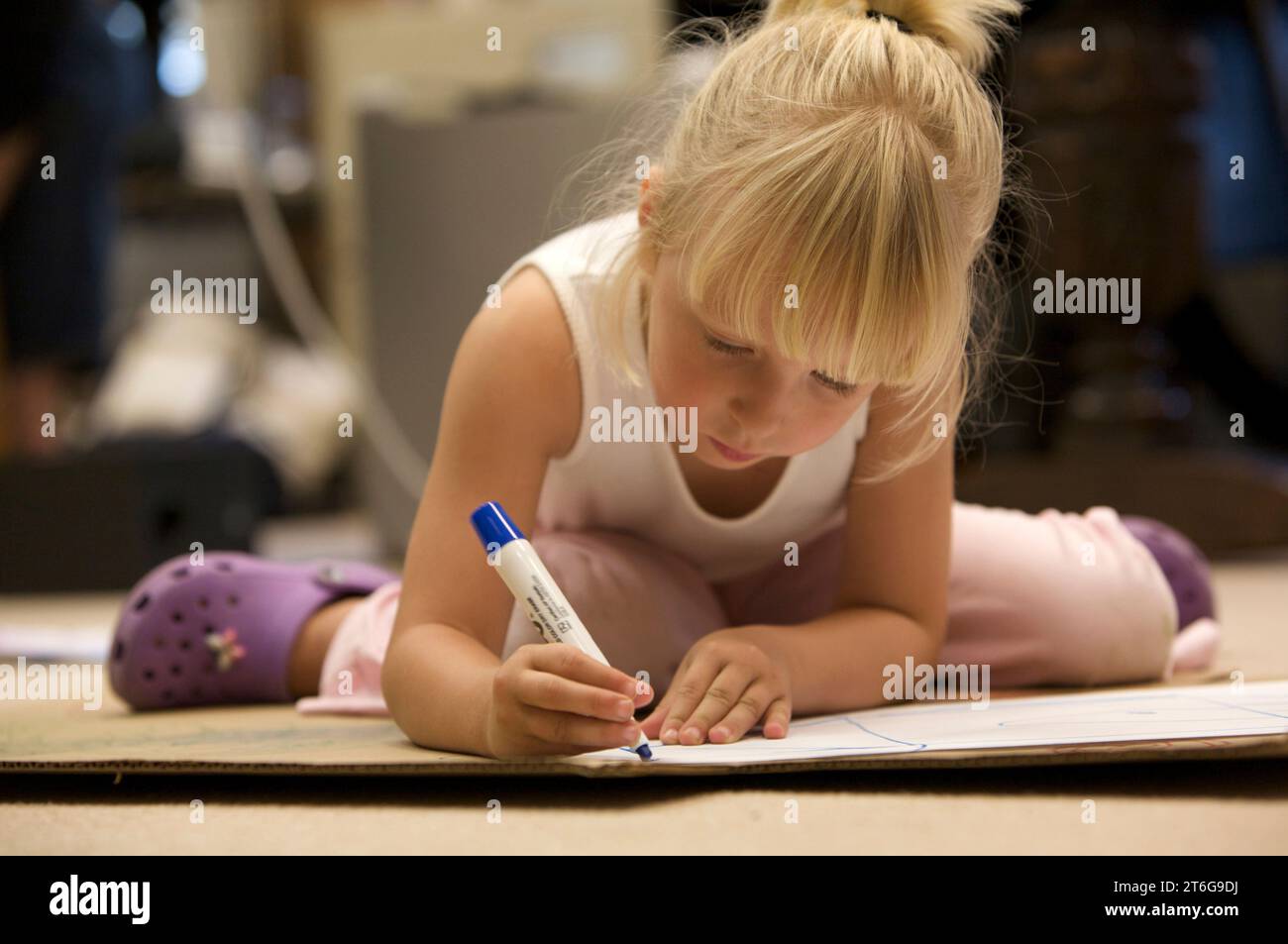 Una bambina prescolare si concentra sulle sue opere d'arte, disegnando con un pennarello. Foto Stock