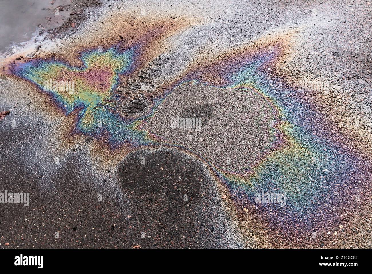 Sfondo colorato astratto di perdite di benzina sull'asfalto bagnato con segni dalle cuffie. Foto Stock