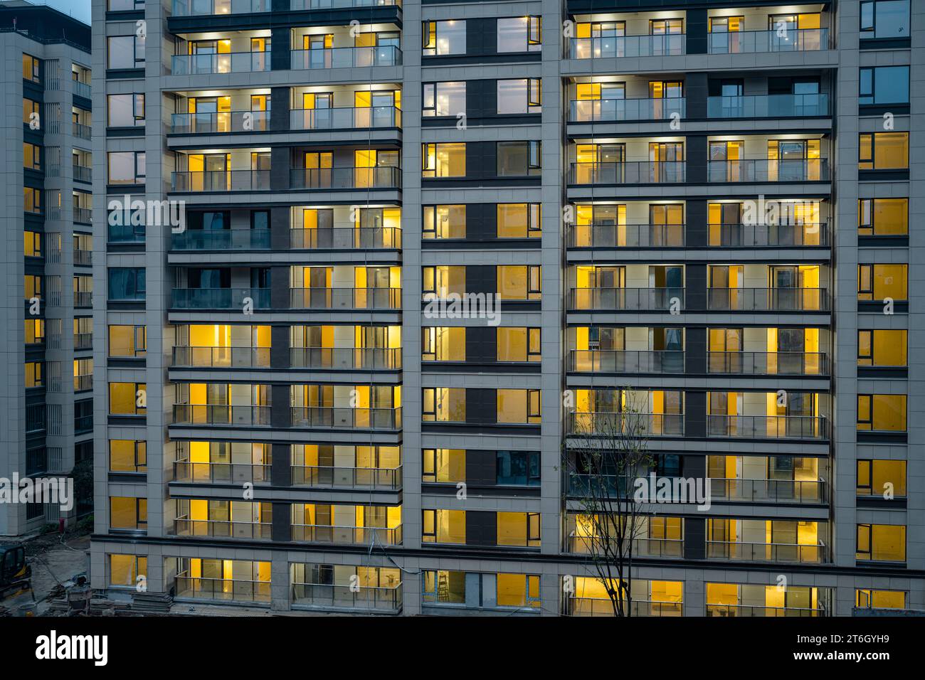 Moderno edificio residenziale illuminato di luci la mattina presto. Foto Stock