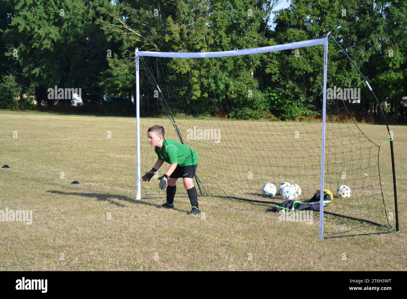 Giovane calciatore maschile in porta - formazione calcio e apprendimento nuove abilità sportive - divertimento e giochi - Sussex UK Foto Stock