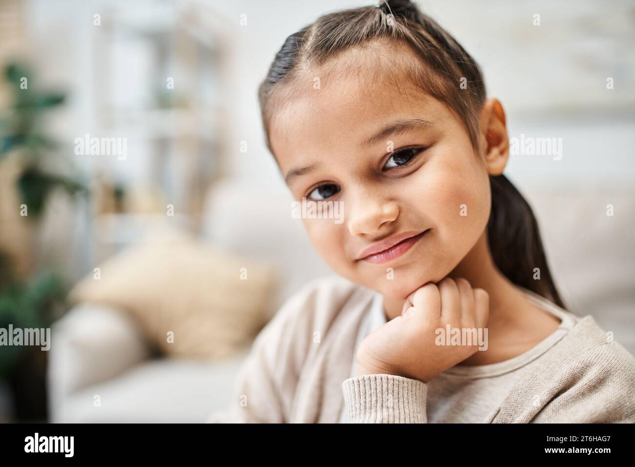 ritratto di una ragazza sorridente dell'età elementare con i capelli bruna che guarda la macchina fotografica in un appartamento moderno Foto Stock