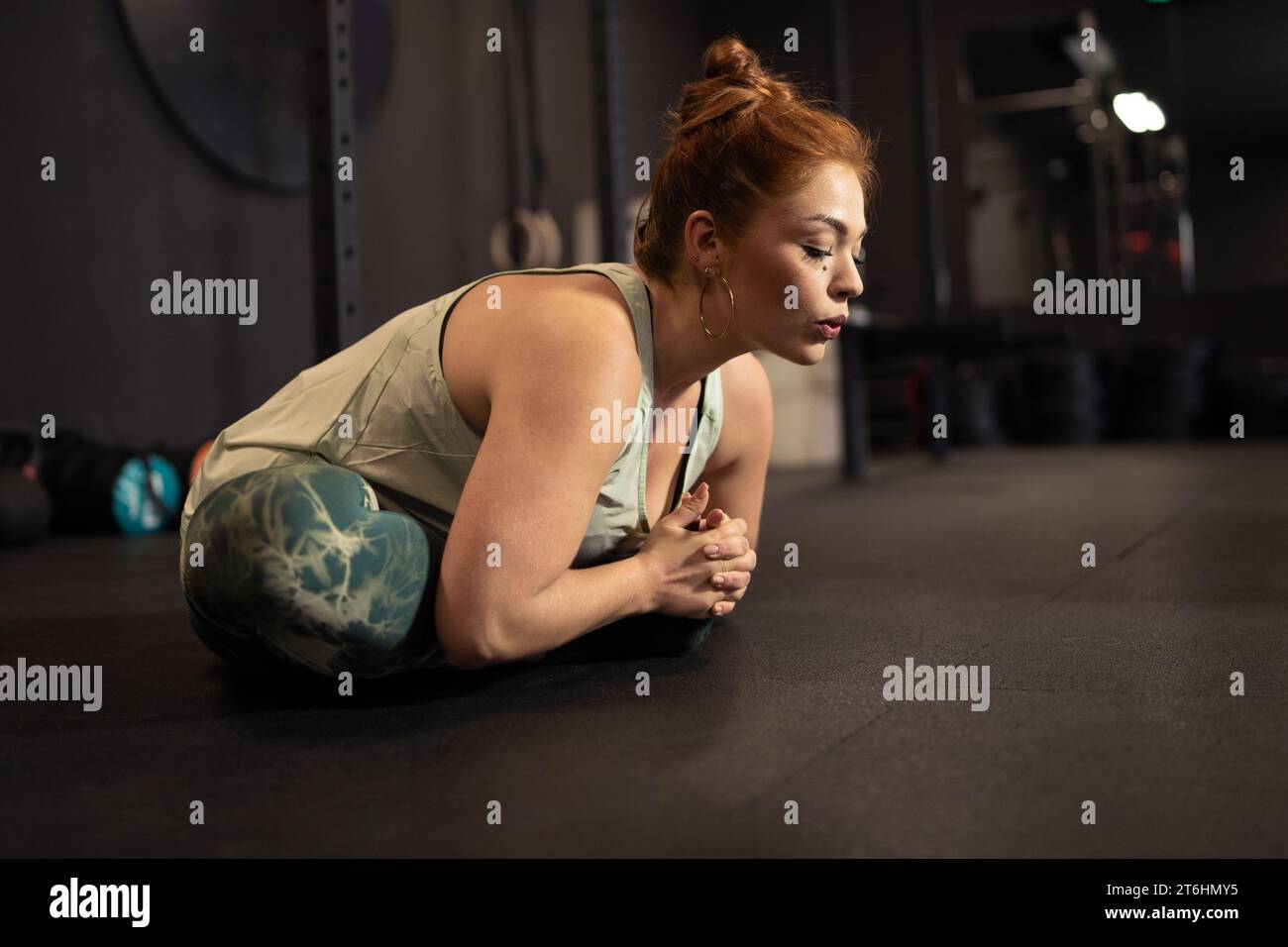 Donna concentrata che esegue uno yoga in palestra, dimostrando tecniche di rilassamento e concentrazione. Foto Stock