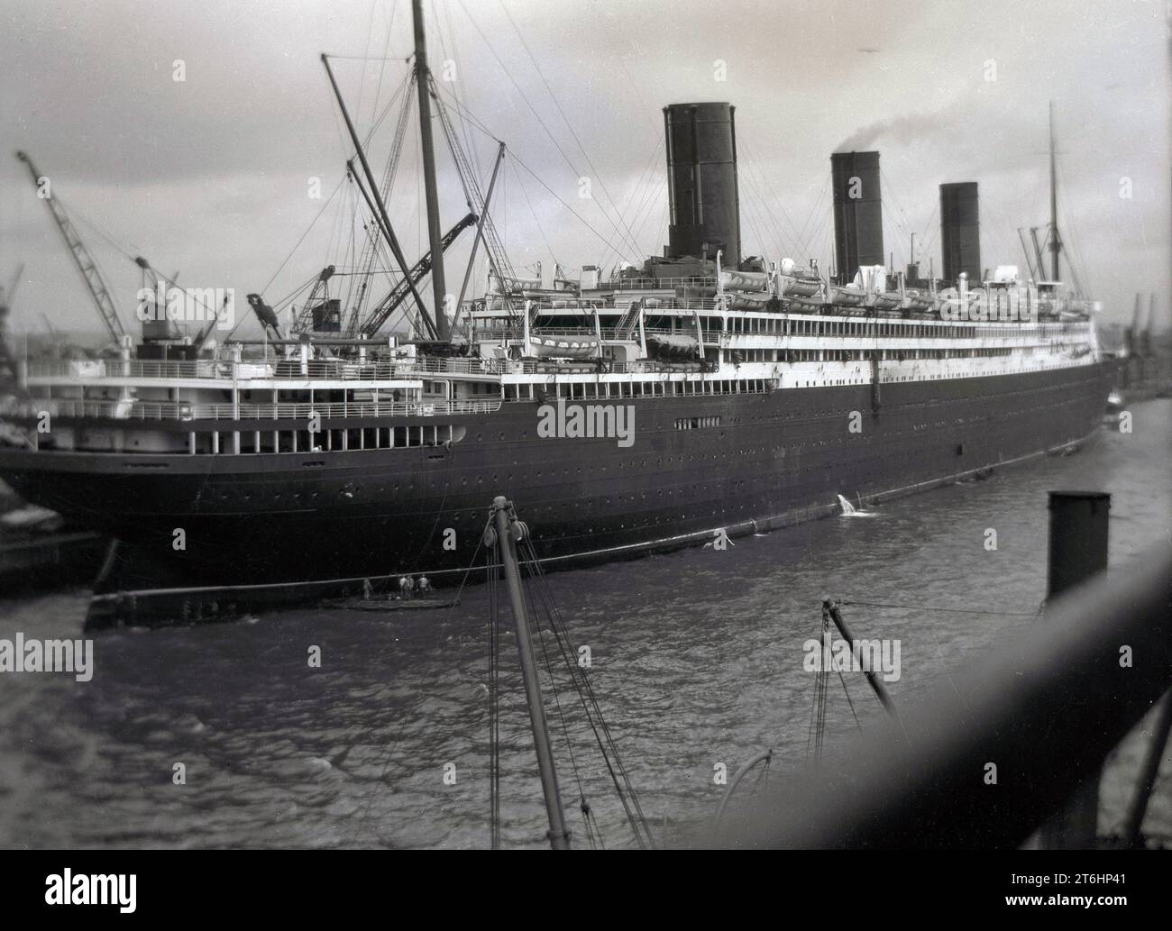 1930, storico, una grande nave passeggeri a vapore a tre imbuti ormeggiata in un molo, Inghilterra, Regno Unito, la RMS Berengaria (ex SS Imperator) a Southampton. Originariamente costruita nei cantieri navali Vulcan di Amburgo, in Germania, e trasportava 83 scialuppe di salvataggio, in grado di ospitare 5.500 persone, quando la costruzione terminò nel 1913, era la nave passeggeri più grande del mondo. Foto Stock