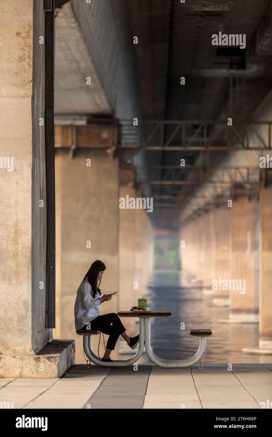 Giovane donna che fa un picnic sotto il ponte al fiume Han, Corea del Sud Foto Stock