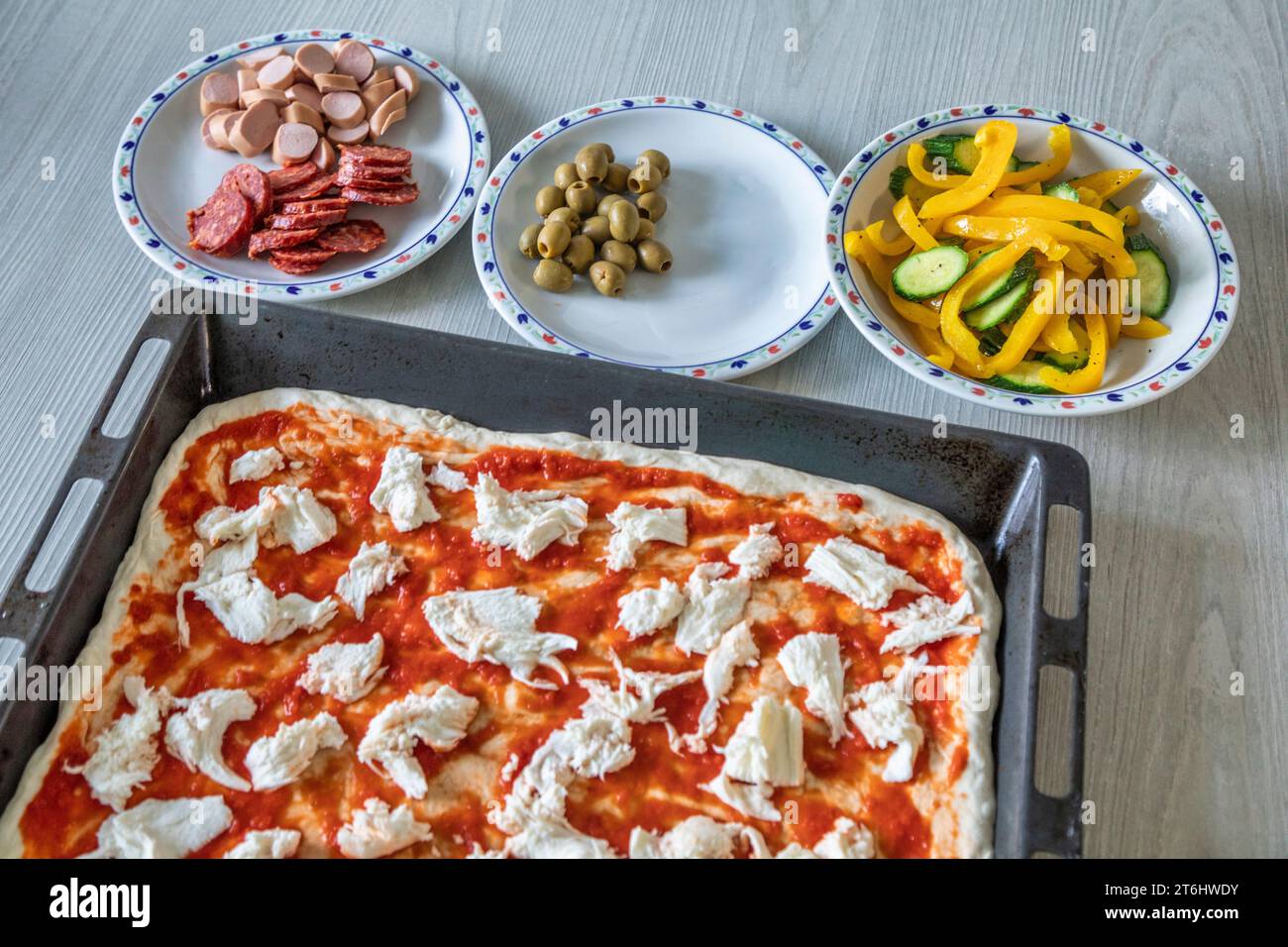 Preparazione della pizza fatta in casa, padella, impasto arrotolato e guarnire gli ingredienti Foto Stock