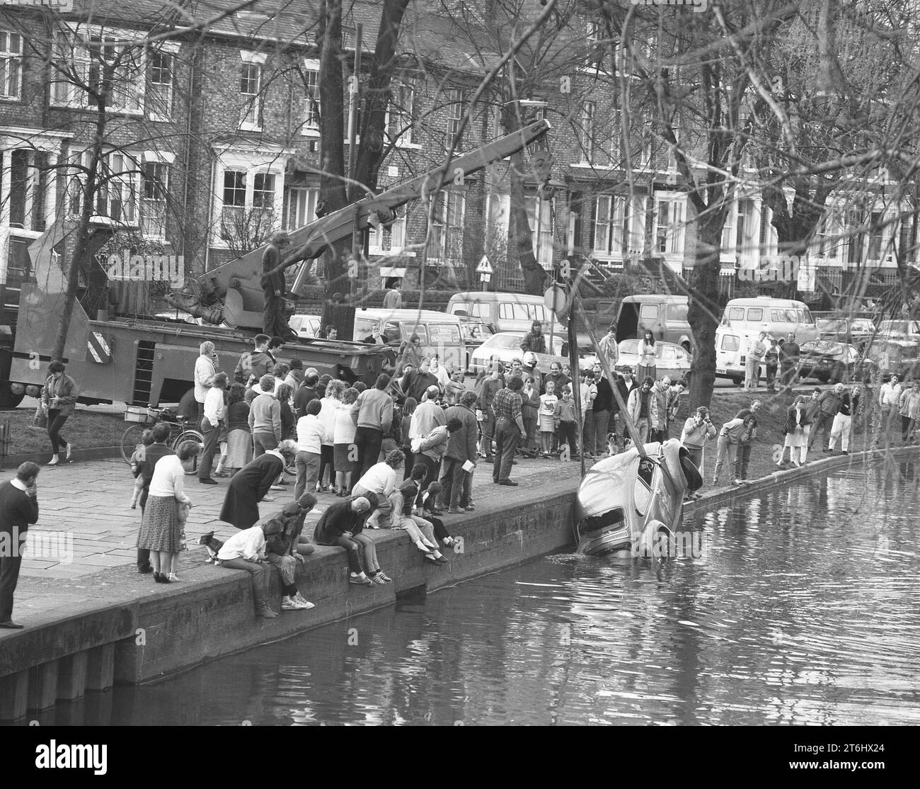 1987, una folla di persone si è riunita su una riva del fiume a guardare un'auto, un Maggiolino VW a due porte, recuperato da un fiume urbano, Inghilterra, Regno Unito, Foto Stock