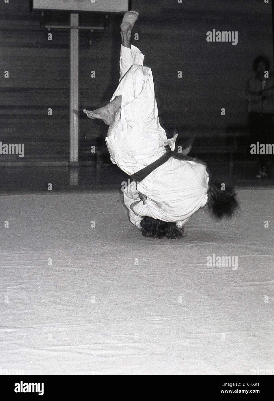Anni '1970, judo, due concorrenti maschili bloccati insieme in combattimento su un tappetino, entrambi capovolti, piedi su, Inghilterra, Regno Unito. L'arte marziale giapponese del Judo è uno sport fisico duro, che coinvolge numerose mosse, ma che richiede anche una forte disciplina mentale, concentrazione e resilienza. Un fattore chiave nel judo è il rispetto, per il tuo avversario e per te stesso. Foto Stock