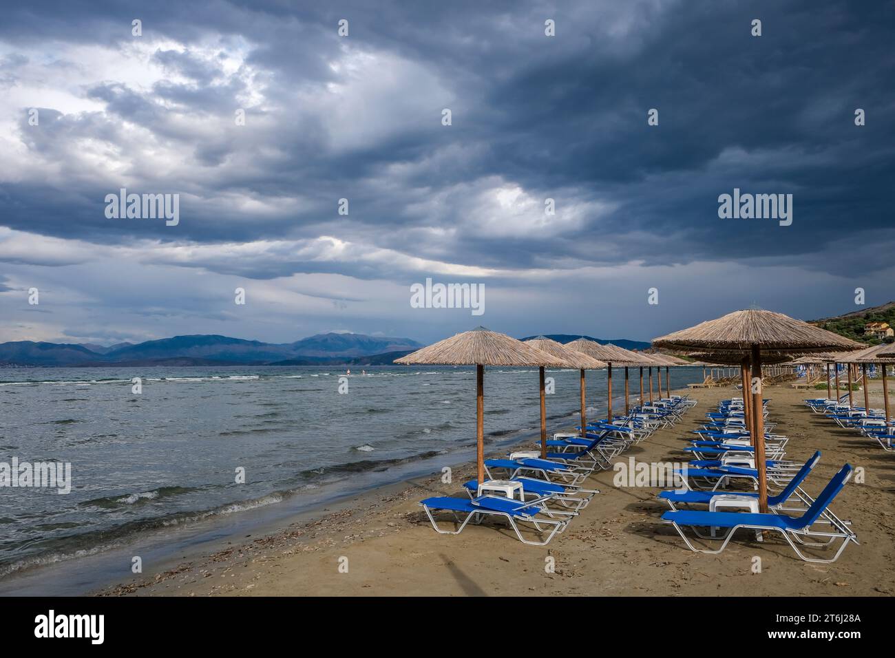 Kalamaki, Corfù, Grecia, lettini e ombrelloni sulla spiaggia di Kalamaki nel nord-est dell'isola greca di Corfù, sullo sfondo della terraferma dell'Albania Foto Stock