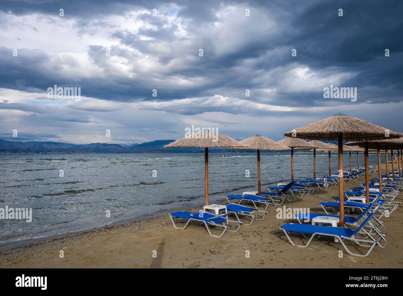 Kalamaki, Corfù, Grecia, lettini e ombrelloni sulla spiaggia di Kalamaki, nel nord-est dell'isola greca di Corfù, sullo sfondo la terraferma dell'Albania con la località balneare di Saranda. Foto Stock