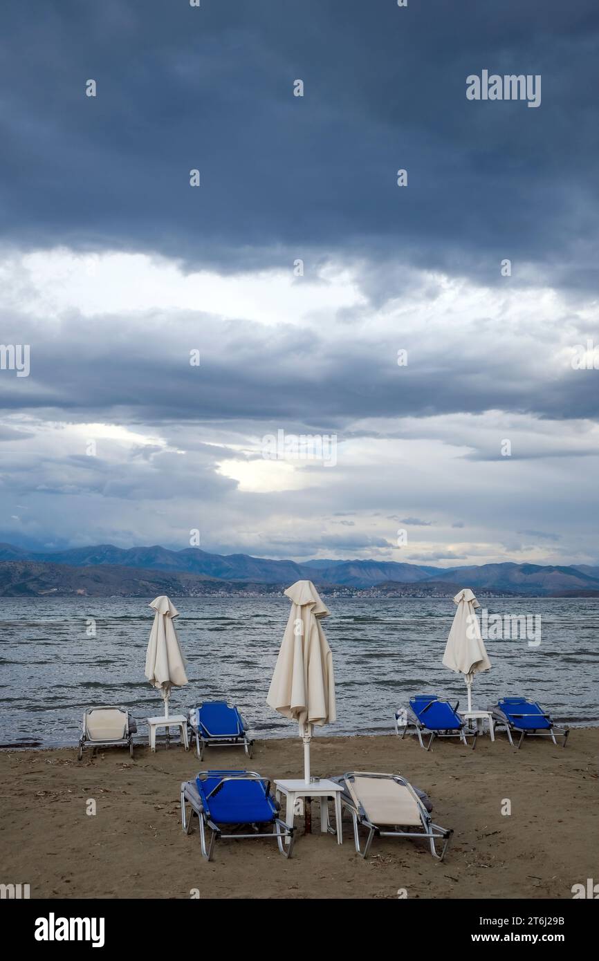 Kalamaki, Corfù, Grecia, lettini e ombrelloni sulla spiaggia di Kalamaki, nel nord-est dell'isola greca di Corfù, sullo sfondo la terraferma dell'Albania con la località balneare di Saranda. Foto Stock