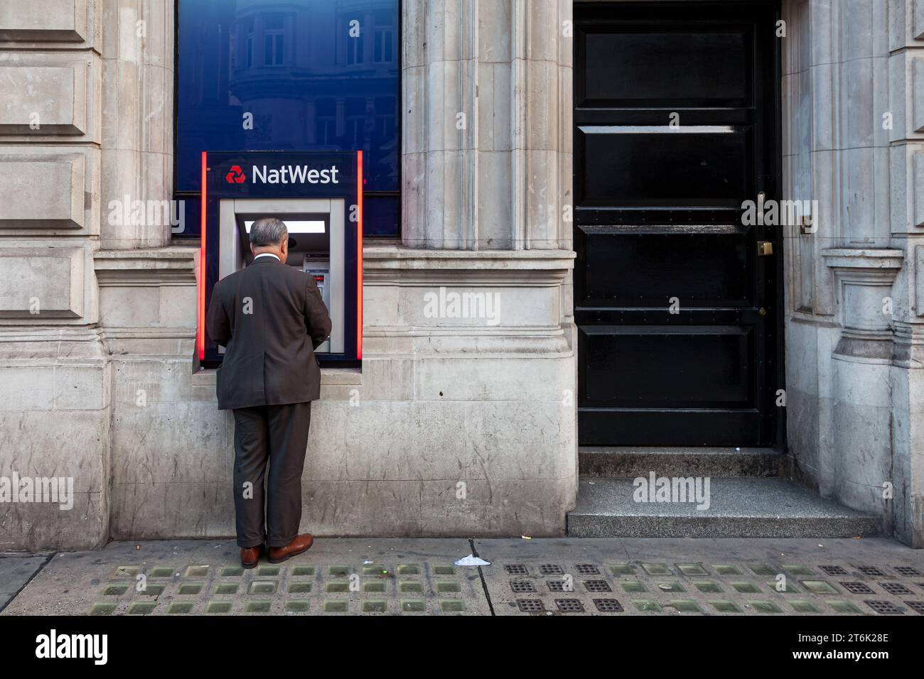 Un uomo usa un bancomat (ATM) appartenente alla National Westminster Bank in una strada vicino a Piccadilly Circus a Londra. REGNO UNITO Foto Stock