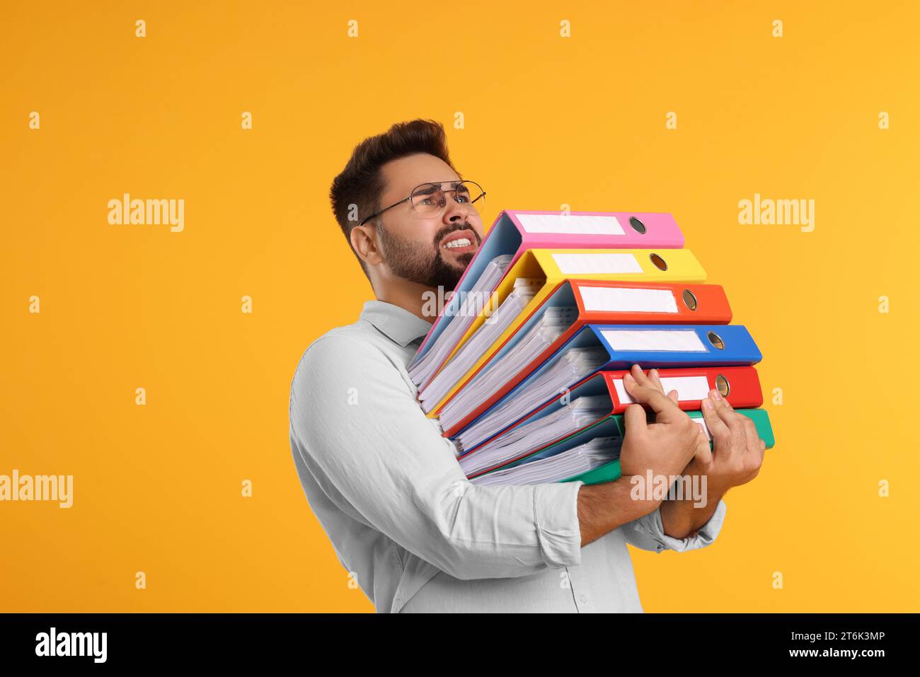 Uomo stressante con cartelle su sfondo arancione, spazio per il testo Foto Stock