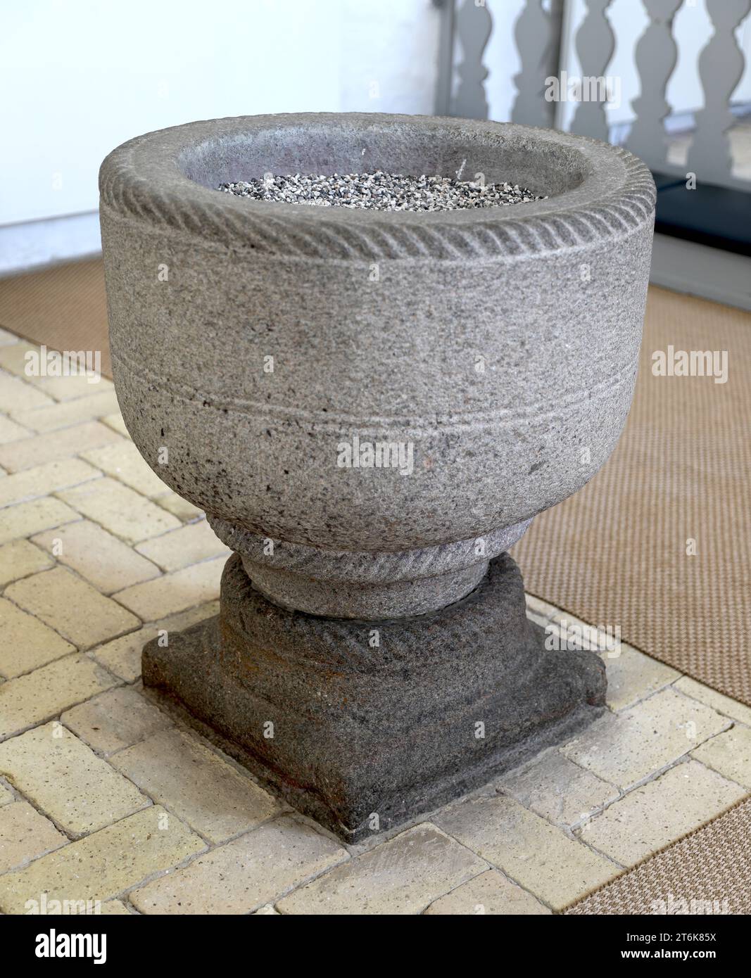 Fonte battesimale del XIII secolo utilizzata come piantatrice nel cortile del castello di Rosenholm, Danimarca. Resti di cerniere del coperchio medievale evidenti sul lato del bacino. Foto Stock