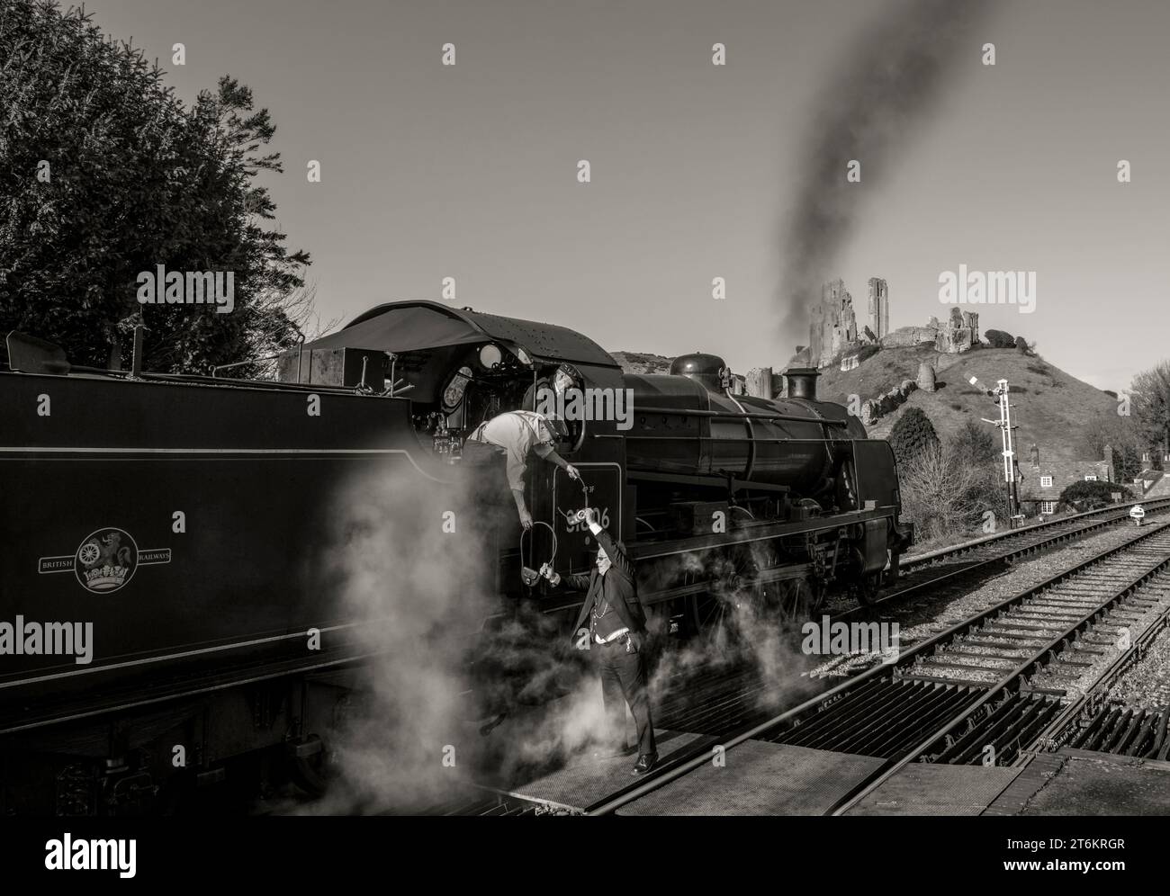 Treno a vapore che passa attraverso la stazione ferroviaria di Corfe con il castello di Corfe Foto Stock