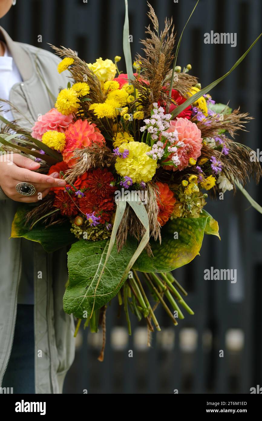 Un grande bouquet di fiori misti nelle mani di una donna. Il lavoro di un fiorista in un negozio di fiori. Foto Stock