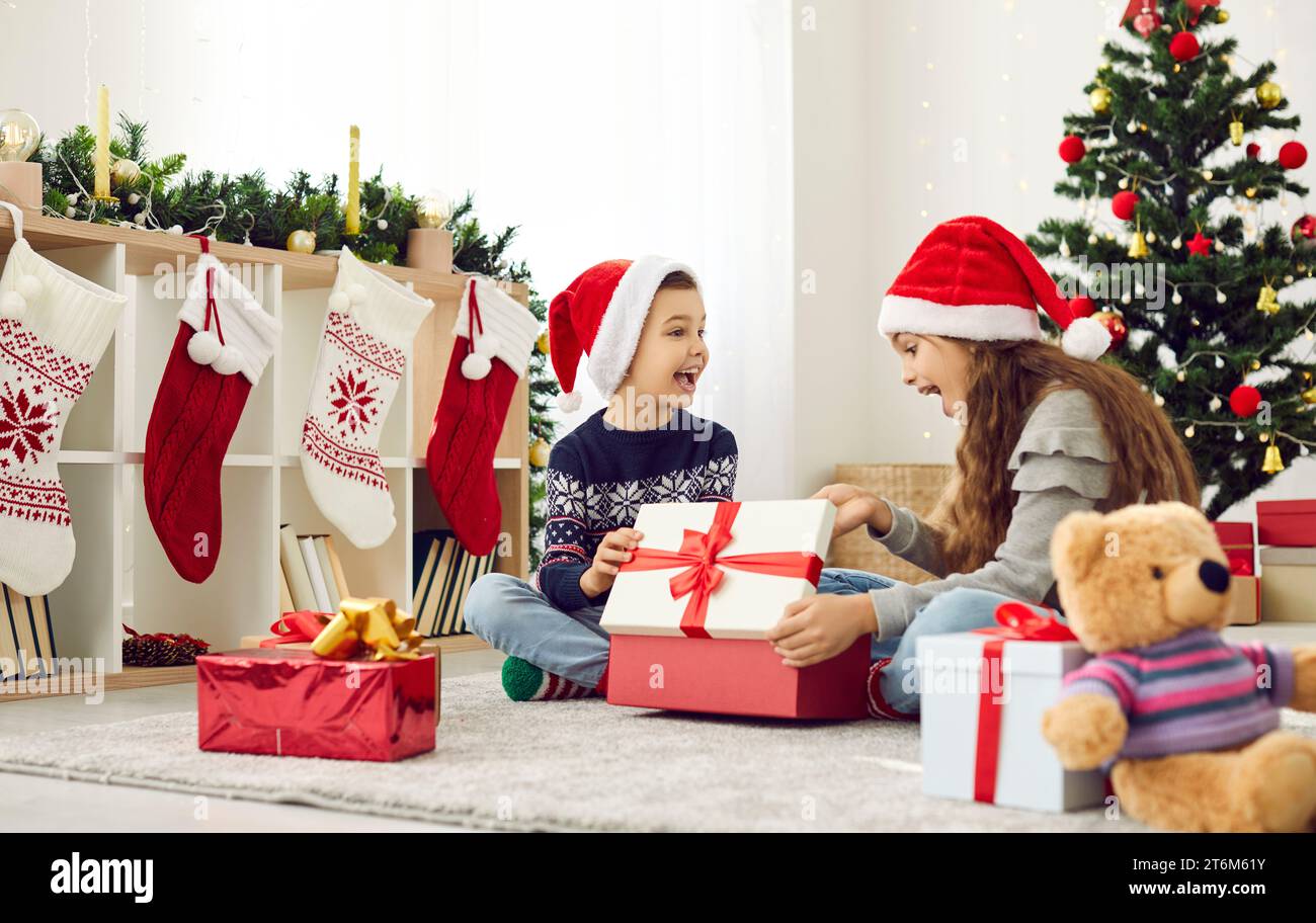 I bambini felici si divertono con i regali di Natale aperti a casa Foto Stock