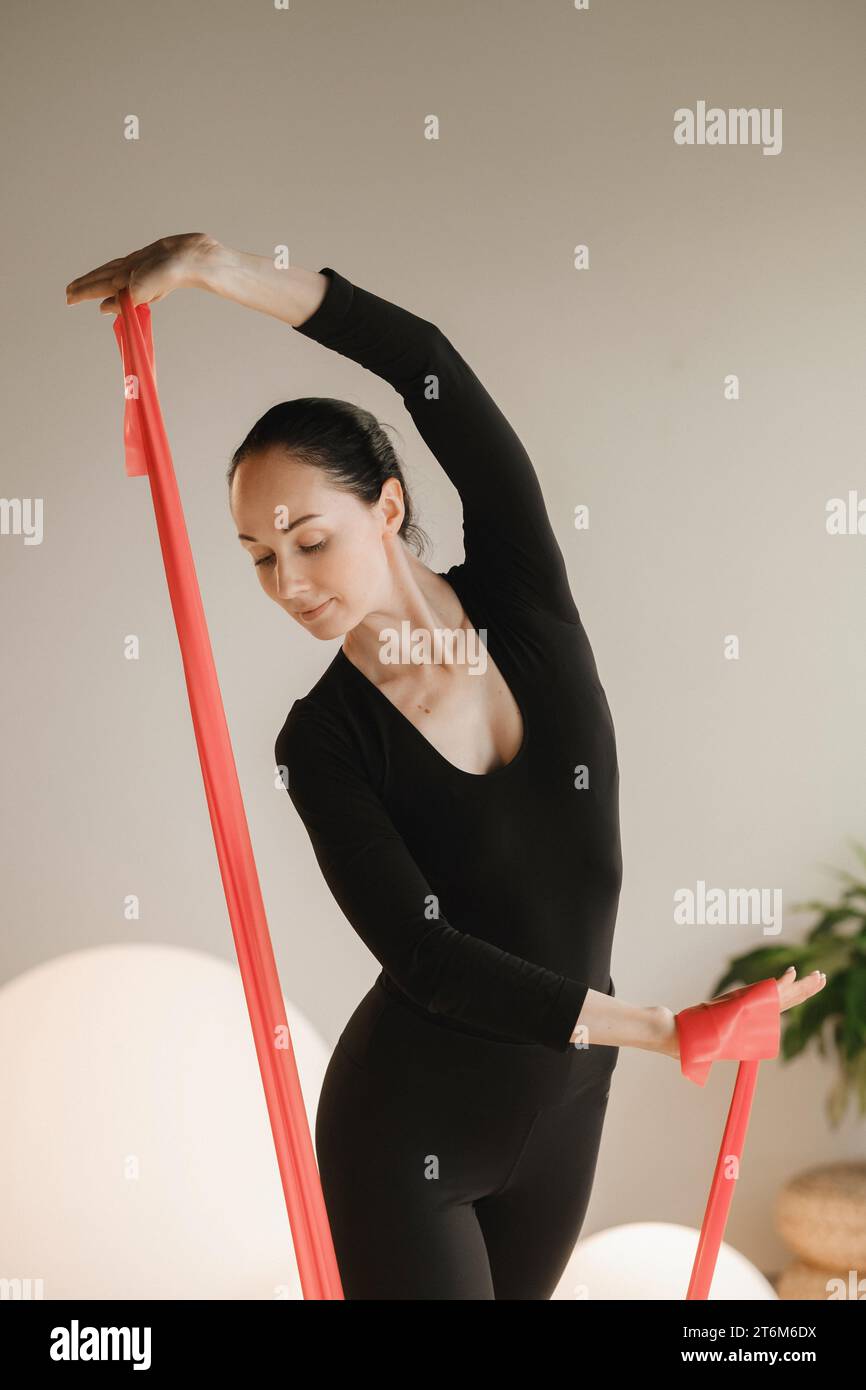 Ragazza di colore nero che fa fitness con nastri rossi al chiuso Foto Stock