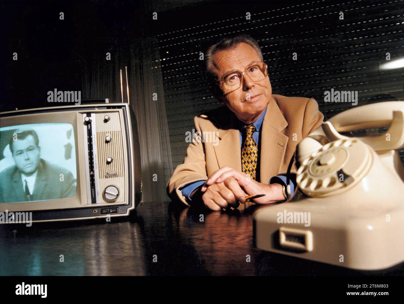 Eduard Zimmermann, Fernsehmoderator von Aktenzeichen X... ungelöst, September 1997 Deutschland, Unterföhring, 23.09.1997, Eduard Zimmermann, 1929-2009, Fernsehmoderator von Aktenzeichen X... ungelöst, in seinem Büro, mit altem Telefon Siemens W 48 und Fernseher von Graetz, beide aus der Zeit um 1967, als die Sendung im ZDF startete, über Video wird Fernsehbild Aktenzeichen von 1967 eingespielt, von 1967 bis Oktober 1997 moderierte Zimmermann 300 XY-Folgen, Verbrechensbekämpfung, Verbrechen, Kriminalität, Schreibtisch, Fernsehgeschichte, TV-Geschichte, TV-Fahndung, Fahndung im Fernsehen, dunkel Foto Stock