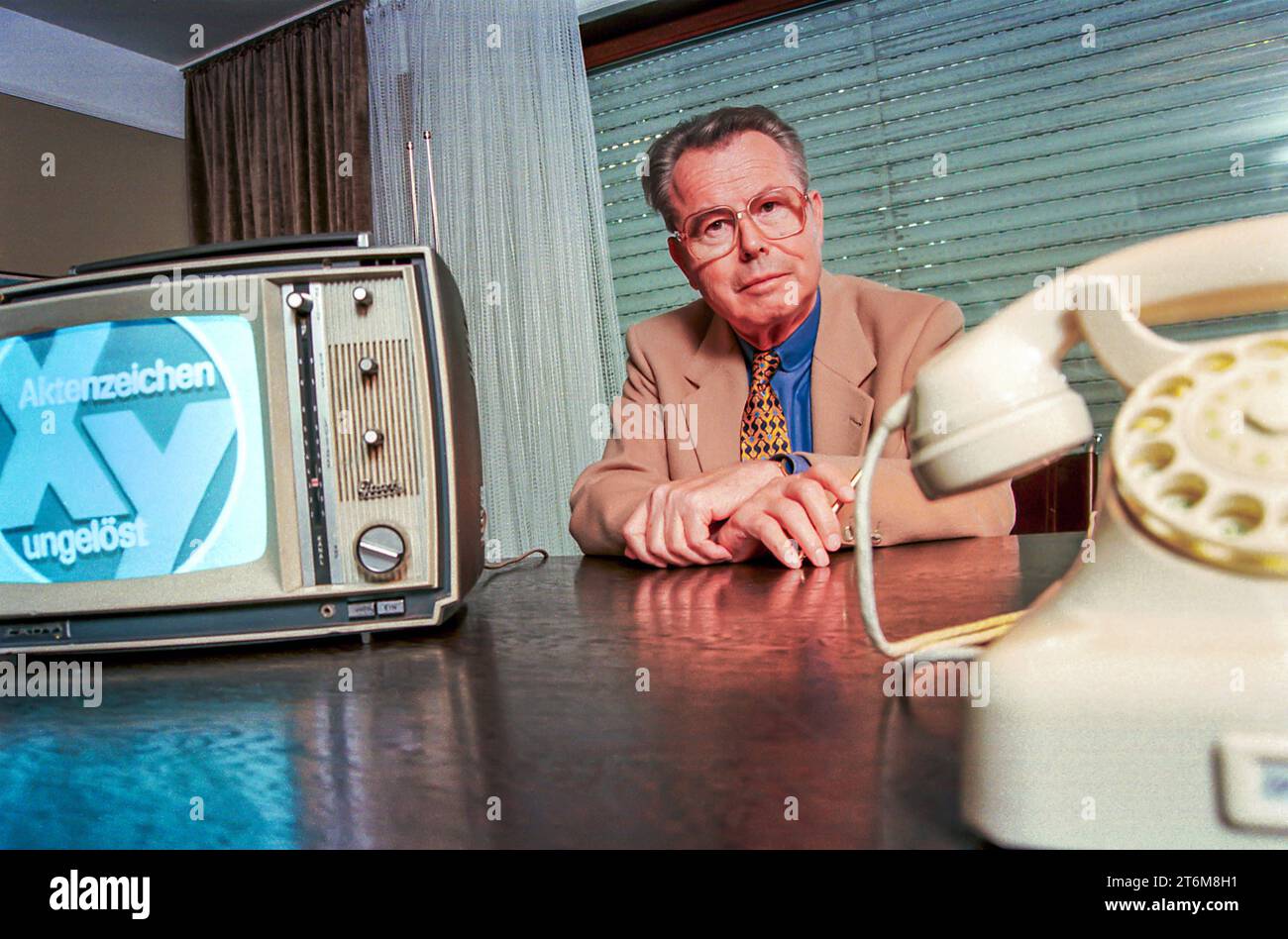 Eduard Zimmermann, Fernsehmoderator von Aktenzeichen X... ungelöst, Unterföhring, September 1997 Deutschland, Unterföhring, 23.09.1997, Eduard Zimmermann, 1929-2009, Fernsehmoderator von Aktenzeichen X... ungelöst, in seinem Büro, mit altem Telefon Siemens W 48 und Fernseher von Graetz, beide aus der Zeit um 1967, als die Sendung im ZDF startete, über Video wird Fernsehbild Aktenzeichen von 1967 eingespielt, von 1967 bis Oktober 1997 moderierte Zimmermann 300 XY-Folgen, Verbrechensbekämpfung, Verbrechen, Kriminalität, Schreibtisch, Fernsehgeschichte, TV-Geschichte, TV-Fahndung, Fahndung im Fer Foto Stock