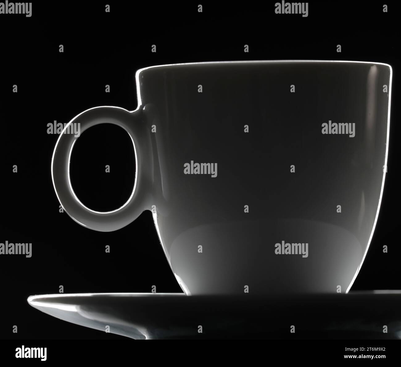 Tazza di caffè in porcellana su un piattino isolato su sfondo nero. Primo piano. Scena da studio con retroilluminazione scura. Foto Stock