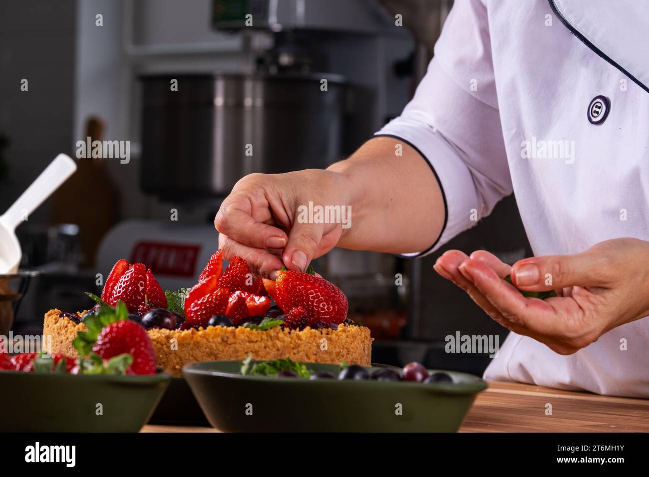 mani femminili che decorano una torta di frutti di bosco. Foto Stock