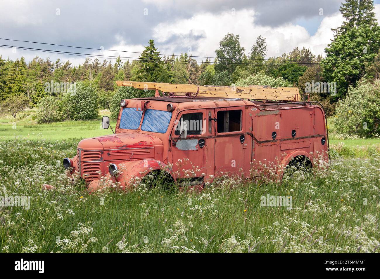 una vecchia macchina antincendio rossa si trova abbandonata in un prato Foto Stock