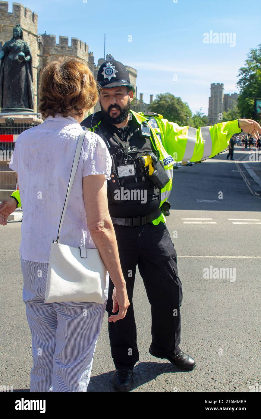 15 giugno 2023 Un agente di polizia in uniforme che dirige i turisti vicino al Castello di Windsor, una famosa residenza reale a Windsor Berkshi Foto Stock