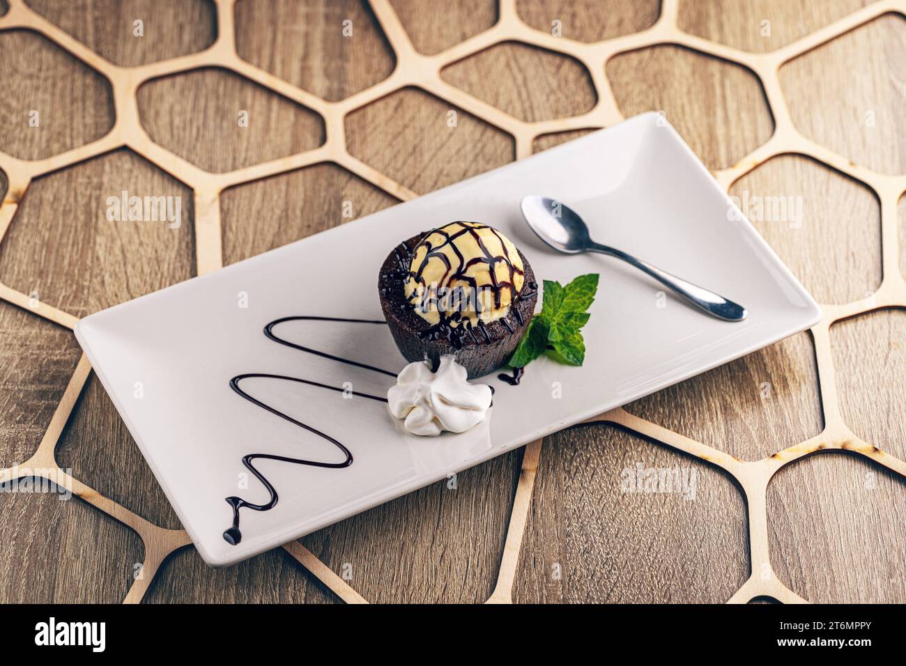 Dolce caldo di lava fondente al cioccolato con paletta per gelato in cima Foto Stock