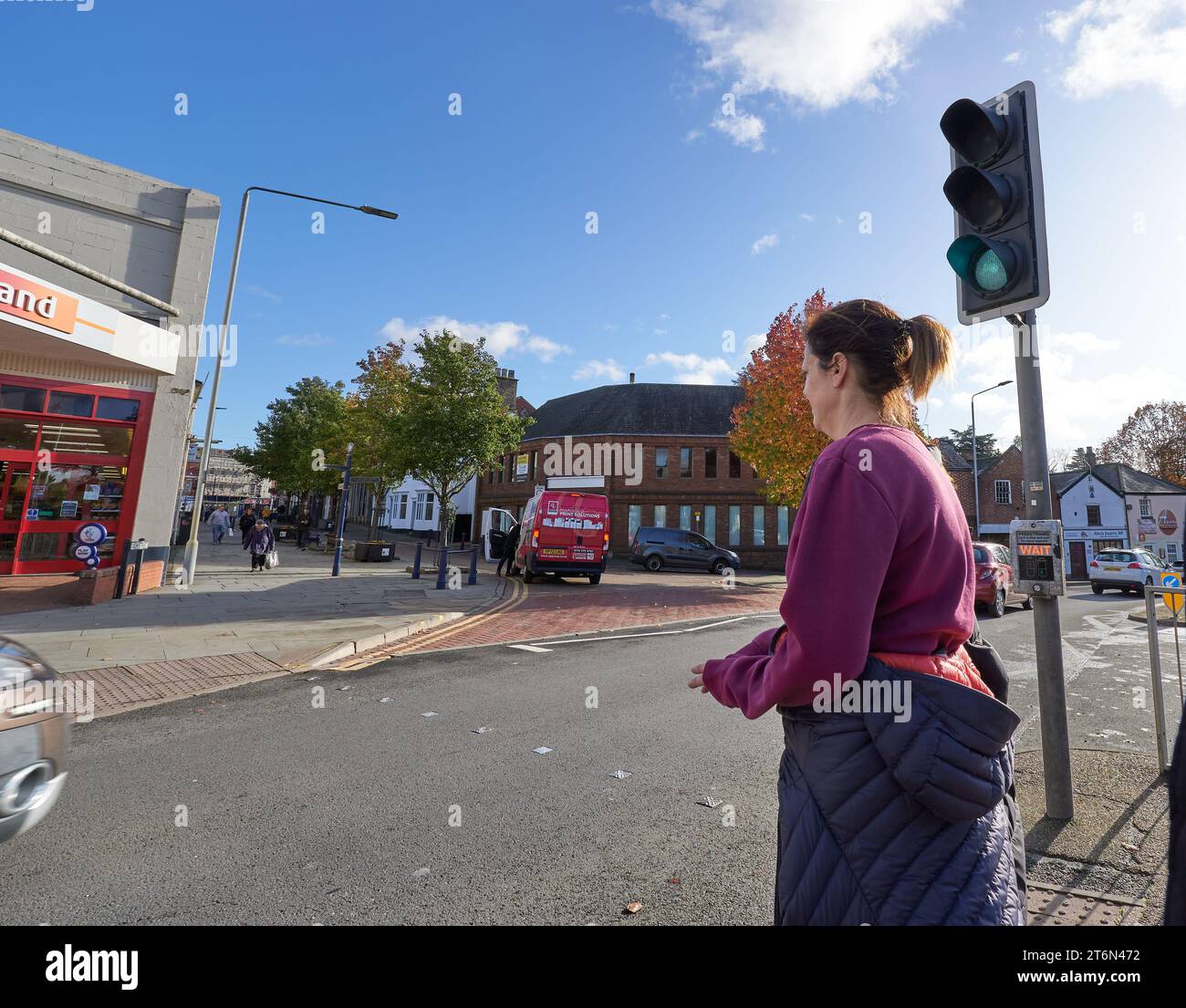 Donna che aspetta di attraversare una strada trafficata a Melton Mowbray, Regno Unito Foto Stock