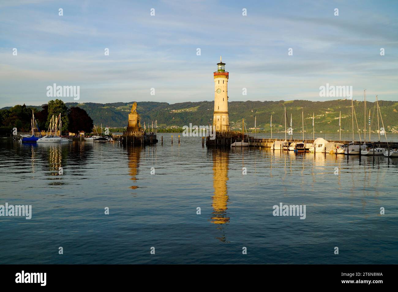 Porto illuminato dal sole e faro di Lindau sul tranquillo lago Costanza (lago Bodensee) con le Alpi sullo sfondo in una calda e soleggiata serata in ottobre Foto Stock