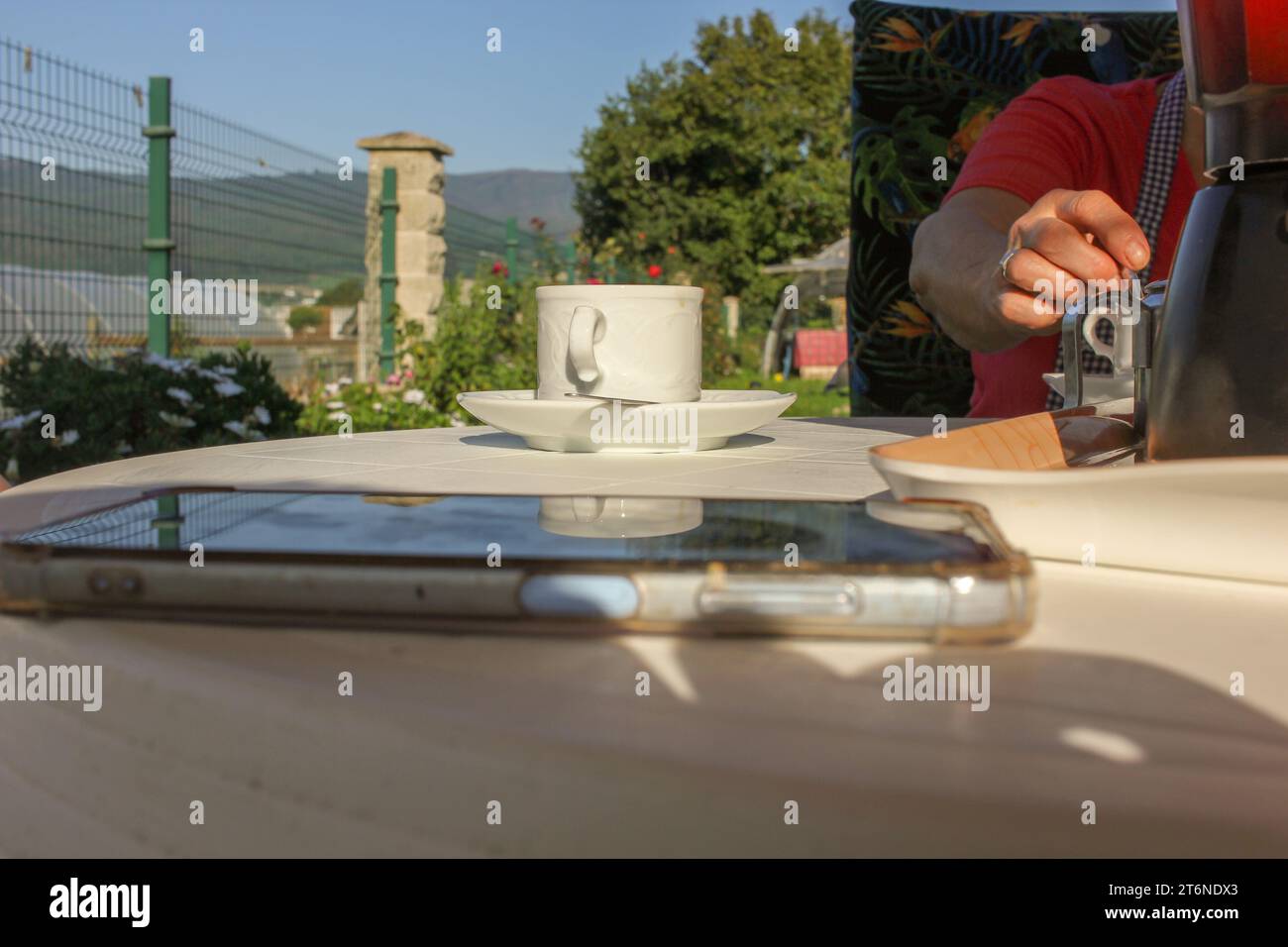muoviti su un tavolo in giardino mentre ti prendi una tazza di caffè Foto Stock